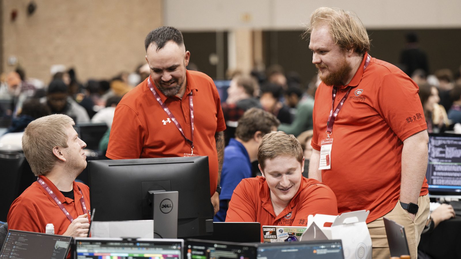Club members at the 2025 DoE CyberForce Competition working at a bank of laptops.